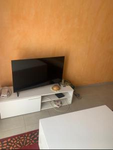 a flat screen tv sitting on top of a white cabinet at Immeuble carrefour 2 in Ngaparou