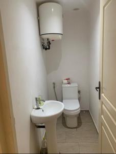 a white bathroom with a toilet and a sink at Immeuble carrefour 2 in Ngaparou