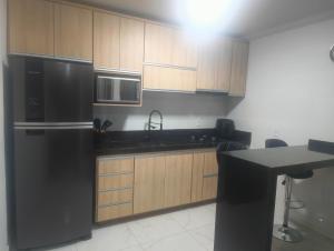 a kitchen with a stainless steel refrigerator and wooden cabinets at Casa Aconchegante in Barbacena