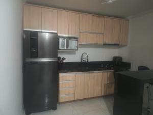 a kitchen with a black refrigerator and wooden cabinets at Casa Aconchegante in Barbacena