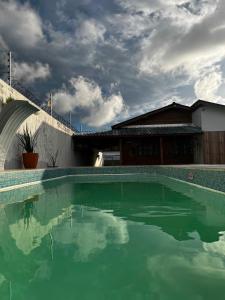 a pool of green water in front of a building at Casa da Brisa in Salinópolis