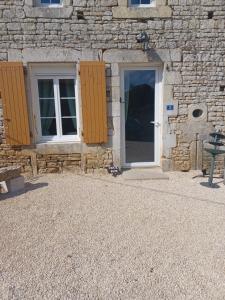 a stone building with a door and windows and a bench at Chez Pépé in Limalonges
