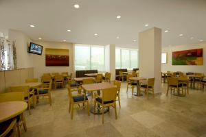 a dining room with tables and chairs and windows at One Coatzacoalcos Forum in Coatzacoalcos
