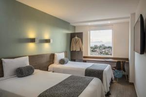 a hotel room with two beds and a window at One Coatzacoalcos Forum in Coatzacoalcos +45 photos
