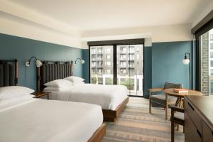 two beds in a hotel room with blue walls at The Junto Hotel in Columbus +123 photos