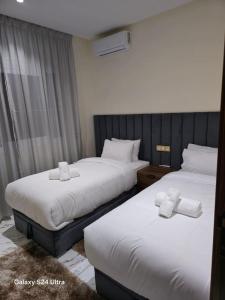 two beds in a hotel room with white sheets at Appart Hôtel Stade Tanger in Tangier