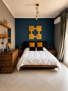 a bedroom with a large bed with a blue wall at Terra boho apartment in Ambelákia