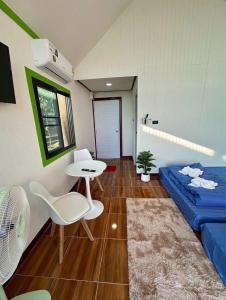 a room with a blue bed and a table and chairs at ปลายเขื่อนแคมป์ปิ้ง บ้านแฟมรี่ in Sirindhorn