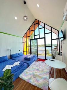 a room with two beds and a table and windows at ปลายเขื่อนแคมป์ปิ้ง บ้านแฟมรี่ in Sirindhorn