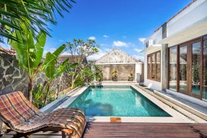 a swimming pool with two chairs and a house at Casa Dijaweqo in Jimbaran