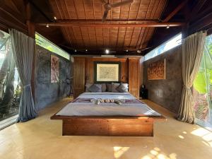 a bedroom with a large bed in a room with windows at Maso Christian Villa Canggu in Tumbak Bayuh