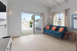 a living room with a blue couch and a sliding glass door at Beach Walk Residences in Palm-Eagle Beach