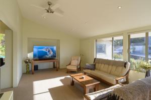 a living room with a couch and a tv at Elevated Views Little Kaiteriteri in Kaiteriteri