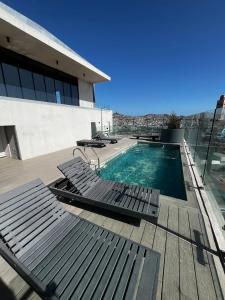 a swimming pool with chaise lounge chairs on a building at Despierta con una vista impecable cada mañana in Coquimbo