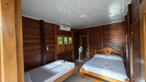 two beds in a room with wood paneling at Mi Ranchito Capurganá in Capurganá