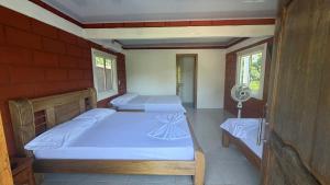 two beds in a room with two windows at Mi Ranchito Capurganá in Capurganá