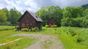a house in the middle of a field with a dirt road at Magiczne Bieszczady - Krzywe 24 in Cisna