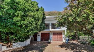 a large white house with a red garage at Private Retreat in Gordonʼs Bay