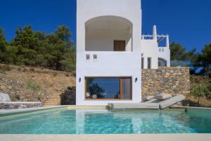 a villa with a swimming pool in front of a house at Vista Portolago Villas & Suites in Lakkíon