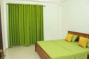 a bedroom with a green curtain and a bed with yellow pillows at Villa Deniyaya in Deniyaya