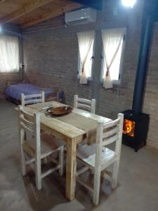 a wooden table and chairs in a room with a fireplace at Refugio de Monte in San Luis +11 photos