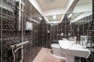 a black tiled bathroom with a sink and a toilet at 구리 호텔 옐로 in Guri +55 photos