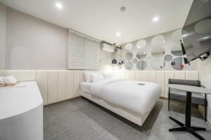 a bedroom with a white bed and a table at 구리 호텔 옐로 in Guri
