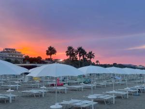a group of white tables and umbrellas on a beach at Suite 58 rooms in Giulianova