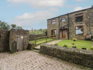 a brick house with a stone wall and a yard at Moscow Mews in Bradford