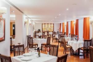 un comedor con mesas y sillas blancas en Parador de Manzanares, en Manzanares