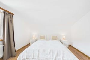 a white bedroom with a white bed and two lamps at Alpine Apartment near Saas-Fee for 4 in Saas-Almagell