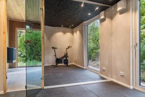 a gym with a treadmill and a bike in a room with windows at Newly Renovated Cottage With Sauna in Melby +17 photos