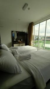 a bedroom with a large white bed with a window at Dwan Hotel in Kota Bharu