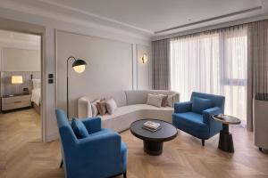 a living room with a couch and two blue chairs at JW Marriott Hotel Kuwait in Kuwait