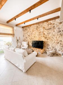 a living room with white furniture and a stone wall at Terra boho apartment in Ambelákia