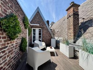a patio with white chairs and a brick building at La cour des grands in Arras