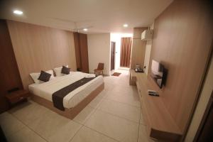 a hotel room with a bed and a television at Empire Suites in Erāttupetta