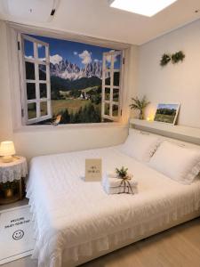 a bedroom with a large white bed with a window at Crystal Ocean House 무료주차 in Kwangan-dong