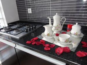 a kitchen counter with two tea pots and red roses at Quintinha dos Queiroses in Vila Boa de Quires