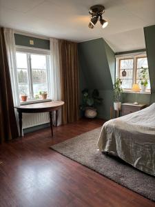 a bedroom with a bed and a table and windows at Sjötomt med bastuflotte & badtunna - lantlig idyll in Vingåker