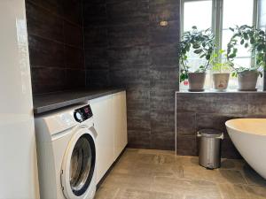 a bathroom with a washing machine and a sink at Sjötomt med bastuflotte & badtunna - lantlig idyll in Vingåker