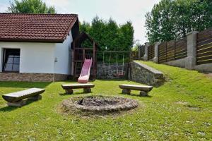 a backyard with a playground with a fire pit and benches at Chalupa u Zíků in Černá v Pošumaví