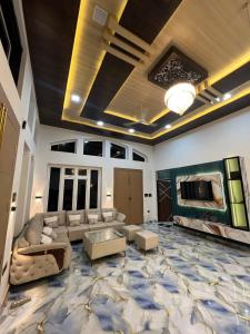 a large living room with a couch and a tv at The Palm Grove Farm Villa in Greater Noida