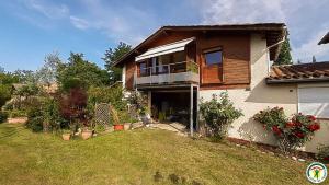 a house with a balcony and a yard at Framboisine in Cazères