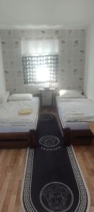 two beds in a room with a rug on the floor at Karczma KOSZARKA in Ploski
