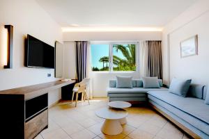 ein Wohnzimmer mit einer blauen Couch und einem Fernseher in der Unterkunft Colonides Retreat Sea & Silence in Vounaria