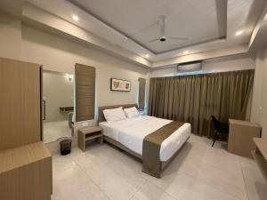 a hotel room with a bed and a desk and a room at Aamys Home in Kalpetta