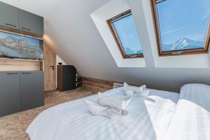 a bedroom with a large white bed with windows at Penzión Šafrán in Ždiar