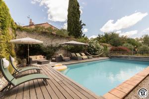 a swimming pool with chairs and umbrellas on a wooden deck at Le sourire des anges in Saint-Élix-le-Château