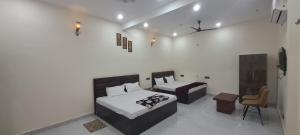a bedroom with two beds and a tv in it at Aashvi Guest House in Ayodhya